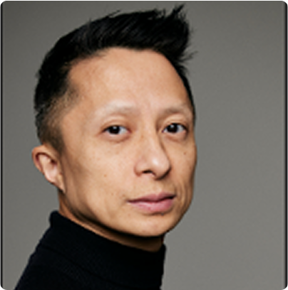 Professional portrait of Kwok One in a dark pinstripe suit against a grey background – corporate headshot with confident expression and formal attire.
