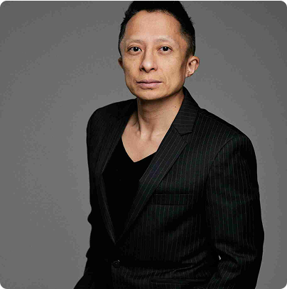 Professional portrait of Kwok One in a dark pinstripe suit against a grey background – corporate headshot with confident expression and formal attire.